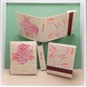 three wedding matchbooks with fun vintage graphics in pinks and coral hues, featuring a diner sign motif with names inside a big heart
