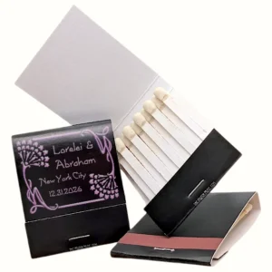 Custom wedding favors: black matchbooks with art nouveau floral design and text 'Lorelei & Abraham, New York City, 12.31.2026'